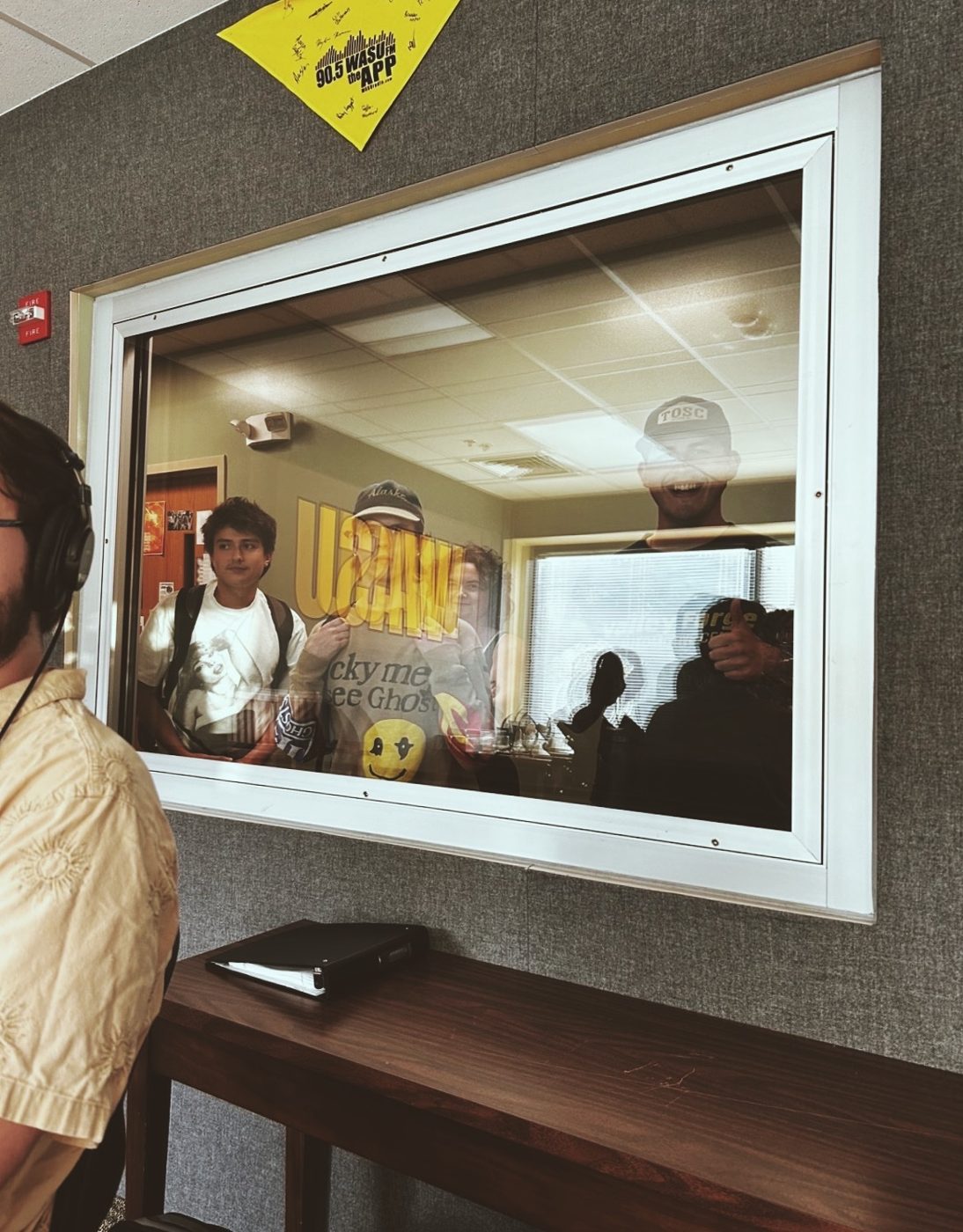 Faces at the studio window while a DJ is on the air.